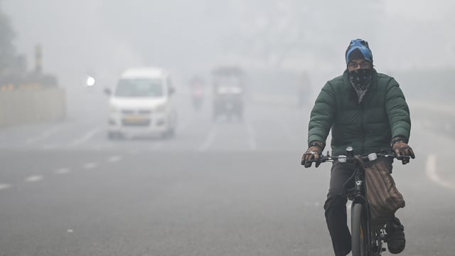 Commuters step out on a cold foggy morning amid rising air pollution.