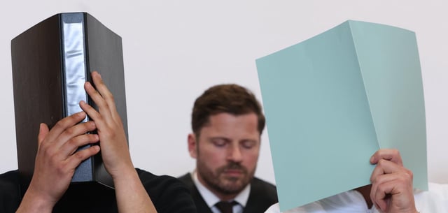Der Hauptangeklagte (r.) verdeckt im März vor dem Landgericht Augsburg sein Gesicht