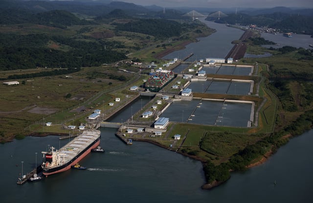 In an aerial view, the container ship Tampa Triumph passes through the Miraflores Locks as it transits the Panama Canal on September 20, 2023 in Panama City, Panama. The Panama Canal Authority is continuing to restrict the number of vessels that pass through the Panama Canal locks as drought has caused water levels at Gatun Lake to drop. The locks depend on millions of gallons of fresh water from the manmade lake to fill locks in Panama City and Colon in order to transit shipping vessels from the Pacific Ocean to the Caribbean Sea. Over one hundred ships are waiting to transit the canal and the backup could delay goods heading to the United States for the holiday season. It takes an average of 8-10 hours for a ship to transit the 50 miles through the canal versus several weeks to travel thousands of miles around Cape Horn and the southernmost parts of South America.