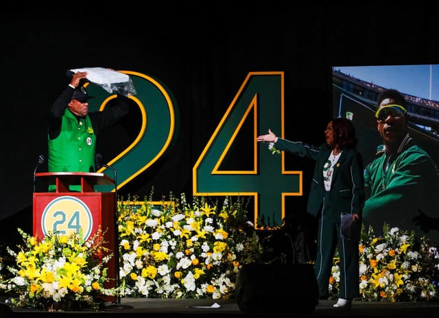 Fred Atkins holds a base after delivering remarks during Rickey Henderson’s Celebration of Life Ceremony at Oakland Arena on Saturday. Radio personality Renel Brooks-Moon, who served as emcee, joins Atkins on stage.
