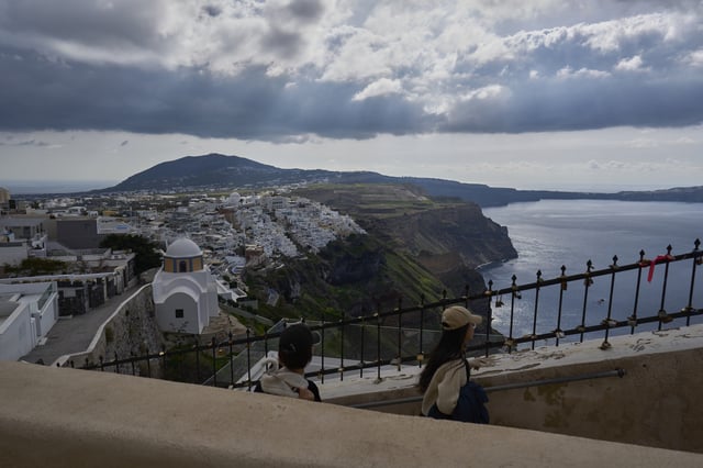 Tourists walk on the narrow streets of Fira town on the popular Aegean Sea holiday island of Santorini, southern Greece, Monday, Feb. 3, 2025, as emergency crews were deployed on the island after a spike in seismic activity raised concerns about a potentially powerful earthquake. (AP Photo/Petros Giannakouris)
