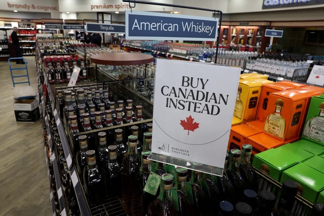 A sign that reads ''Buy Canadian Instead'' is displayed on top of bottles, hanging above another sign that reads "American Whiskey", after the top five U.S. liquor brands were removed from sale at a B.C. Liquor Store, as part of a response to U.S. President Donald Trump's 25% tariffs on Canadian goods, in Vancouver, British Columbia, Canada, February 2, 2025. REUTERS/Chris Helgren/File Photo