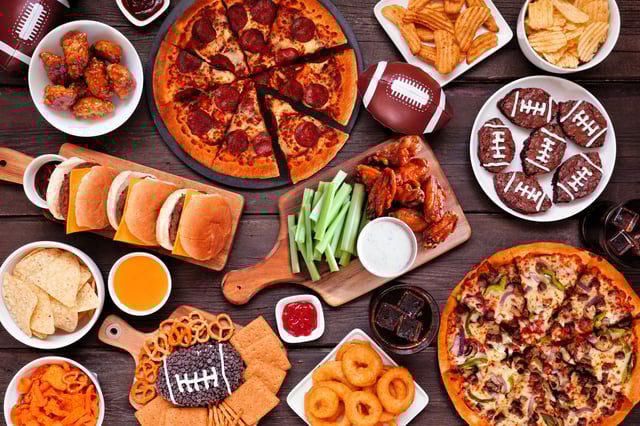 A stock image of a spread of popular foods eaten during the Super Bowl, such as hot wings, burgers, pizza and brownies. The “perfect plate” of food to watch the Super Bowl includes barbecued meat, wings, a seven-layer dip and brownies, according to a December 2024 survey of Americans.