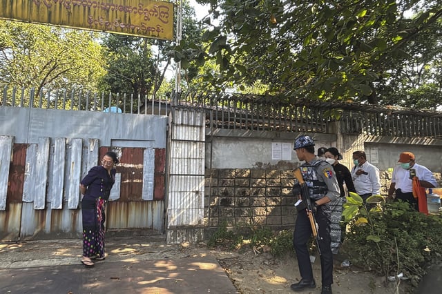 A police officer provides security while unidentified legal officials from Kamayut district court arrive outside the residence of ousted leader Aung San Suu Kyi as the home is auctioned in Yangon, Myanmar, Wednesday, Feb. 5, 2025. (AP Photo/Thein Zaw)