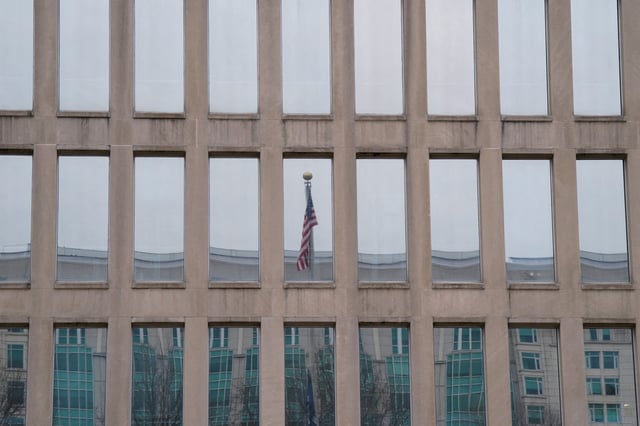 An American flag is reflected in the window of the Office of Personnel Management (OPM) headquarters as people gather to protest, after the Elon Musk-led Department of Government Efficiency (DOGE) was charged with oversight of OPM, in Washington, U.S. February 2, 2025.  REUTERS/Kent Nishimura/File Photo