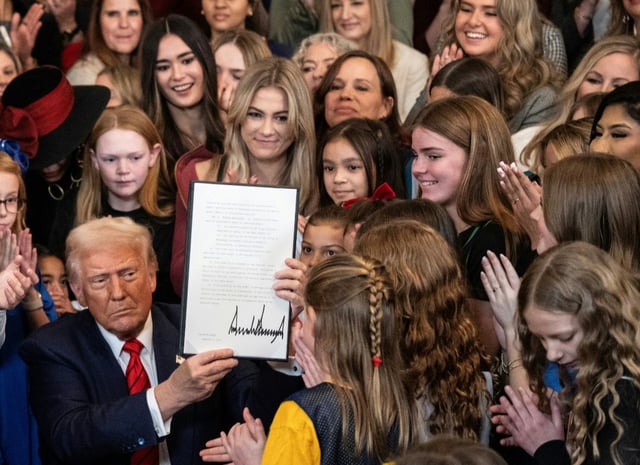 US President Donald Trump holds up a newly signed executive order that seeks to ban transgender female athletes from participating in women's sports