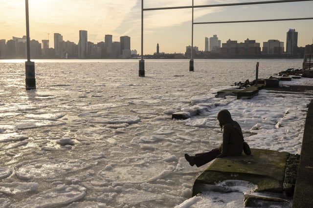 FILE - A person sits on the pier as ice floats on the Hudson River, Jan. 23, 2025, in New York. (AP Photo/Yuki Iwamura, File)