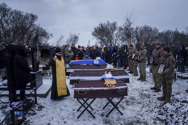 A priest blesses coffins of Kateryna Zapishnya, 38, Diana Zapishnya, 12, Danyil Zapishnyi, 8, and Serhii Zapishnyi, 40, who were killed on Feb. 1 by a Russian strike on residential building of Poltava, during a funeral ceremony in Dykanka, Ukraine, Wednesday, Feb. 5, 2025. (AP Photo/Evgeniy Maloletka)