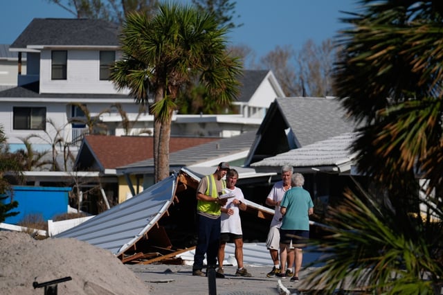 Property owners speak with an official as they process the damage to their homes and community following Hurricane Milton, on Manasota Key, in Englewood, Fla., Sunday, Oct. 13, 2024. (AP Photo/Rebecca Blackwell)