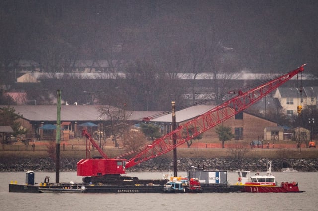 A crane floats on the Potomac River while removing wreckage from an American Airlines plane on Feb. 6, 2025, in Arlington, Virginia. An American Airlines flight from Wichita, Kansas, collided midair with a military Black Hawk helicopter while on approach to Ronald Reagan Washington National Airport on Jan. 29, 2025 outside of Washington, D.C.