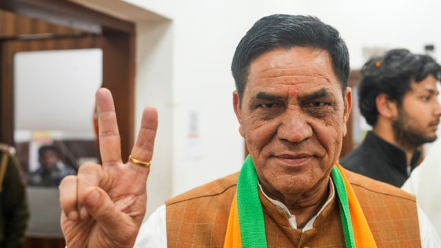 Newly elected MLA Mohan Singh Bisht flashes victory sign before a meeting after the victory in Delhi Assembly elections, at the Delhi state office in New Delhi, Sunday.