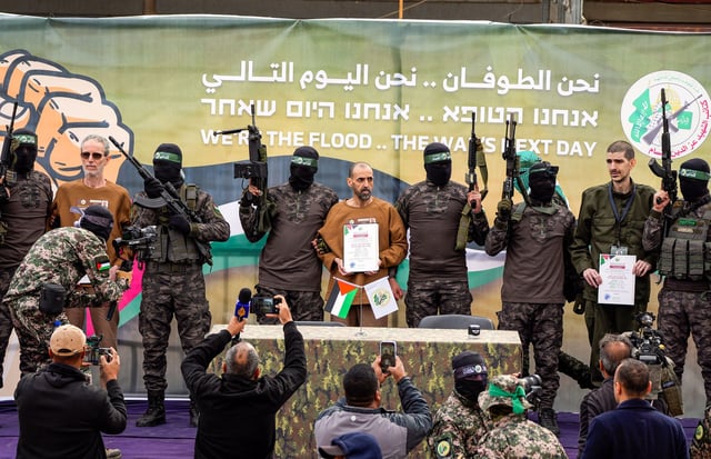 Israeli hostages Ohad Ben Ami, Eli Sharabi and Or Levy stand next to Hamas fighters on a stage before being handed over to the Red Cross in Deir al-Balah, Gaza, on Saturday.