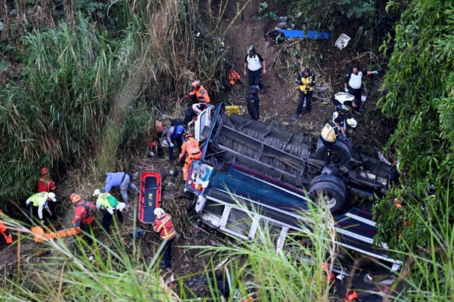 Firefighters and police work at the scene of an accident in which a bus fell down a ravine in Guatemala City on February 10, 2025. A bus carrying 75 people plunged into a ravine in Guatemala City on Monday, killing at least 31 people, rescue workers said.