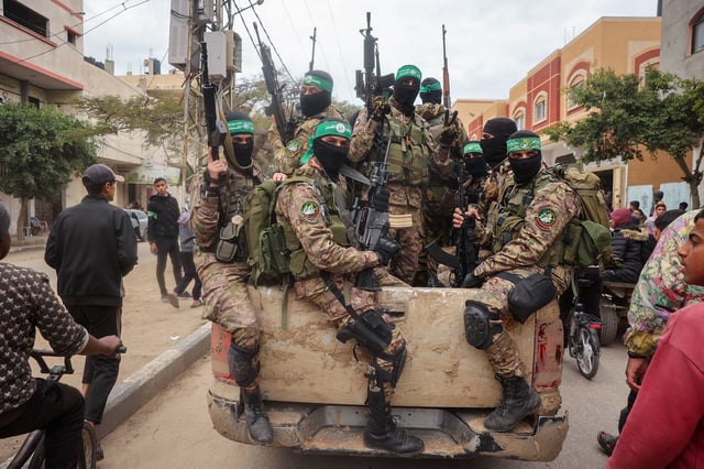 Hamas fighters patrol a street before the handover of three Israeli hostages to a Red Cross team in Deir el-Balah, Gaza, on Saturday.