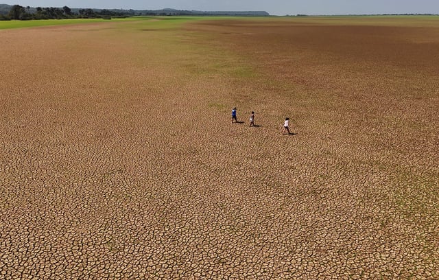 People walking on the dry bed of the Tapajos river during an intense drought, in Tapajos National Forest, Para state, Brazil October 10, 2024.