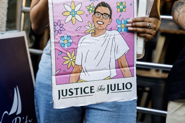 People hold signs for a vigil commemorating Julio Ramirez in New York on June 8, 2022.