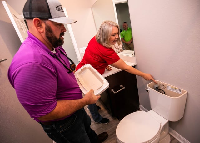 Florida Water Star Program Coordinator Robin Grantham, center, with Southwest Florida Water Management District, points out a low flush toilet in a home in Weybourne Landing in 2022.
