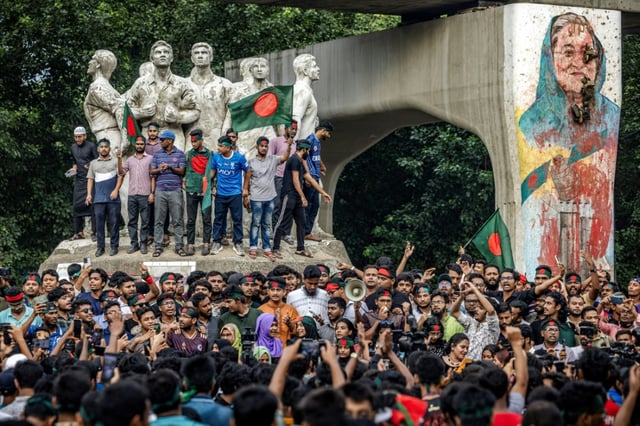 Students protest next to a mural of Bangladesh's ousted premier Sheikh Hasina