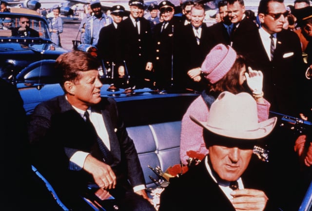Texas Governor John Connally adjusts his tie (foreground) as US President John F Kennedy (left) &amp; First Lady Jacqueline Kennedy (in pink) settled in rear seats, prepared for motorcade into city from airport, Nov. 22. After a few speaking stops, the President was assassinated in the same car.