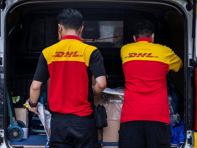 DHL employees prepare numerous packages inside the delivery van parked on the street in Hong Kong.