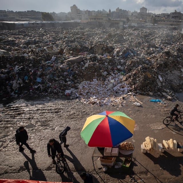 Palestinians walk past a pile of burning garbage, as there is no refuse collection in the city and people are disposing of their rubbish in the streets, in Gaza City, Wednesday, Feb. 12, 2025. (AP Photo/Jehad Alshrafi)