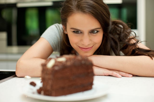 Stock image of a woman eyeing up a piece of cake.