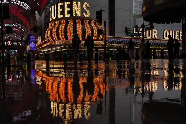People walk along Fremont Street in the rain Thursday, Feb. 13, 2025, in Las Vegas. (AP Photo/John Locher)