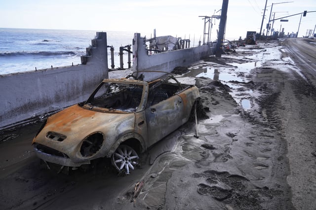 A fire-damages vehicle is left in front of a beach front property after a storm Friday, Feb. 14, 2025, in Malibu, Calif. (AP Photo/Damian Dovarganes)