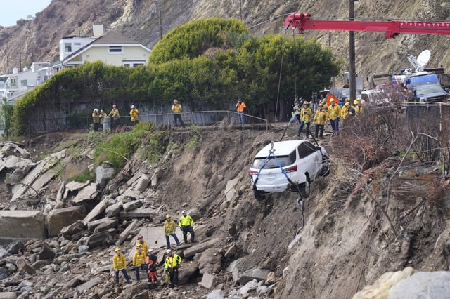 An emergency vehicle is pulled out of the water a day after it was pushed into the surf by a debris flow caused by heavy rainfall, Friday, Feb. 14, 2025, in Malibu, Calif. (AP Photo/Damian Dovarganes)