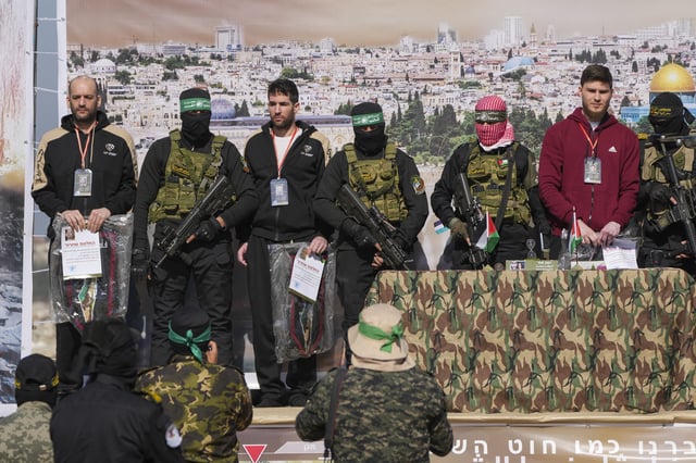 Israeli hostages Iair Horn, 46, left, Sagui Dekel Chen, 36, center left, and Alexander Troufanov, 29, right, are escorted by Hamas and islamic Jihad fighters as they are handed over to the Red Cross in Khan Younis, Gaza Strip, Saturday, Feb. 15, 2025.