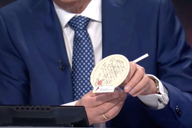 Günther Jauch zeigt den Bierdeckel, auf dem Friedrich Merz 2003 eine mögliche Steuerberechnung für eine Familie mit einem Einkommen von 42.000 Euro notiert hatte