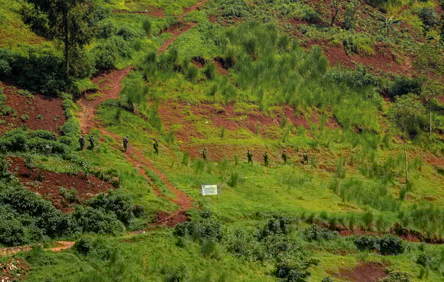 Members of the M23 rebel group walk in a formation, as they patrol across Rusizi river near the Rusizi border crossing point, as Congolese civilians who fled from Bukavu, eastern Democratic Republic of Congo, following clashes between M23 rebels and the Armed Forces of the Democratic Republic of the Congo (FARDC), return home, in Rusizi district, Rwanda, February 17, 2025. REUTERS/Stringer