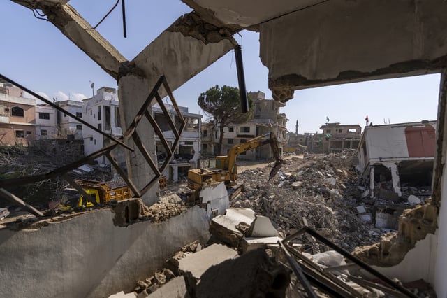 A bulldozer equipped with a drill works on the rubble of destroyed houses, caused by the Israeli air and ground offensive, in the town of Khiam, southern Lebanon, Monday, Feb. 17, 2025. (AP Photo/Hassan Ammar)