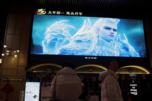 People stand near a giant screen showing a trailer for the Chinese movie "Nezha 2", at a cinema in Beijing, China February 6, 2025. REUTERS/Florence Lo/File Photo