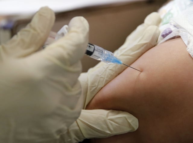File photo of Rambo Islas, 8 months, being held by his mother Maria Islas, as he gets a vaccine shot administered by RN Nicole Ives at the Dallas County Health &amp; Human Services immunization clinic in Dallas, taken on March 8, 2019.