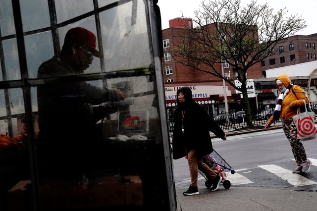 Pedestrians cross the street as a man sorts berries inside a grocery store in Forest Hills, a neighbourhood in the Queens borough of New York City, U.S., May 2, 2022. REUTERS/Bing Guan/File Photo