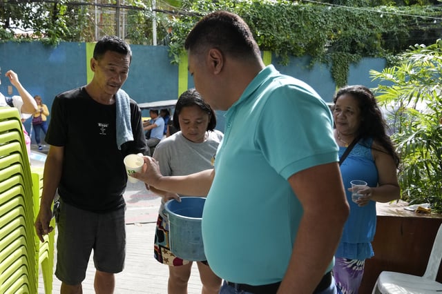 Village chief Carlito Cernal, center, inspects residents holding containers with mosquitos that they captured in Mandaluyong city, Philippines as their village started offering bounty for captured mosquitos, dead or alive, as part of an anti-dengue campaign on Wednesday, Feb. 19, 2025. (AP Photo/Aaron Favila)