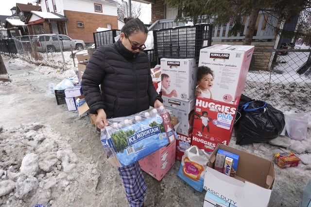 Rosie Mersa carries water to her home Wednesday, Feb. 19, 2025 after a recent water main break caused flooding in Detroit. (AP Photo/Paul Sancya)
