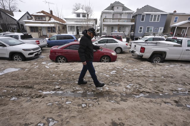 Shlaco Rosario walks down his street through dirt Wednesday, Feb. 19, 2025 after a recent water main break caused flooding in Detroit. (AP Photo/Paul Sancya)