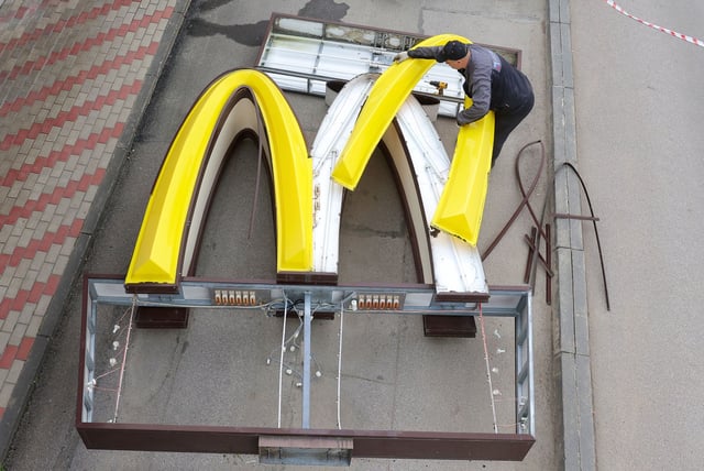 A worker dismantles a pair of golden arches while removing the logo signage from a McDonald's in the town of Kingisepp, in the Leningrad region of Russia, on June 8, 2022.