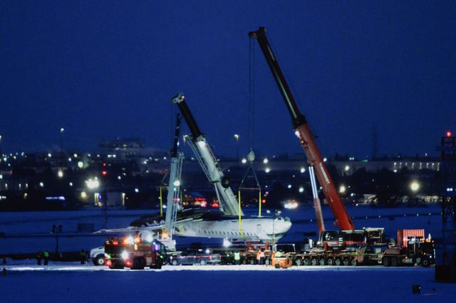 The wreckage of a Delta Air Lines operated CRJ900 aircraft is hoisted onto a truck on the runway as cleanup begins after a plane crash at Toronto Pearson International Airport in Mississauga, Ontario, Canada, on February 19, 2025.