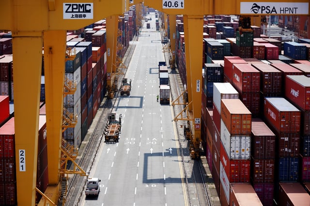A truck driver stands next to his truck as he gets ready to transport a shipping container at Pusan Newport Terminal in Busan, South Korea, July 1, 2021.  REUTERS/Kim Hong-Ji/File Photo