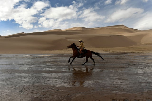 Ranchlands head wrangler Skye Challener runs with her horse Walker through Medano Creek at the base of the Great Sand Dunes during a ride near the Medano-Zapata ranch on March 10, 2021. (Photo by Helen H. Richardson/The Denver Post)
