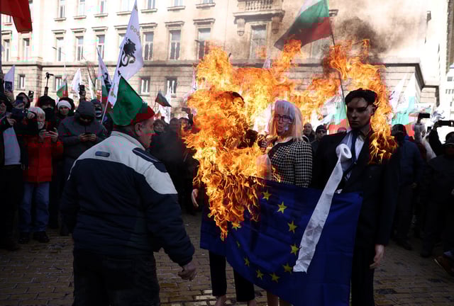 A supporter of Bulgaria's ultranationalist Revival party walks in front of a burning effigy of Christine Lagarde, President of the European Central Bank and an EU flag during a demonstration against the country's plans of joining the euro zone, in Sofia, Bulgaria February 22, 2025. REUTERS/Stoyan Nenov