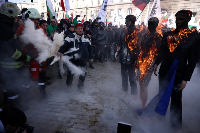 A supporter of Bulgaria's ultranationalist Revival party tries to stop a firefighter from extinguishing a burning effigy of Christine Lagarde, President of the European Central Bank and an EU flag during a demonstration against the country's plans of joining the euro zone, in Sofia, Bulgaria February 22, 2025. REUTERS/Stoyan Nenov