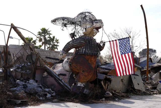 An American flag is suspended from a charred bunny sculpture at the Bunny Museum, which was destroyed by the Eaton Fire in January, Monday, Feb. 17, 2025, in Altadena, Calif. (AP Photo/Chris Pizzello)