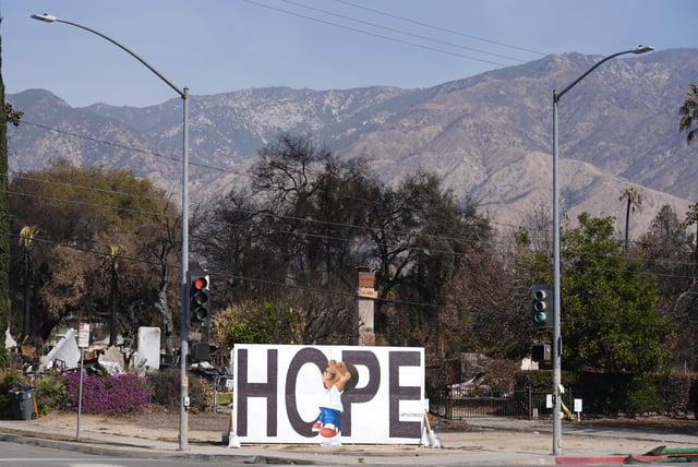 A mural sits in front of a burned property on Woodbury Avenue a month after the Eaton Fire, Monday, Feb. 17, 2025, in Altadena, Calif. (AP Photo/Chris Pizzello)