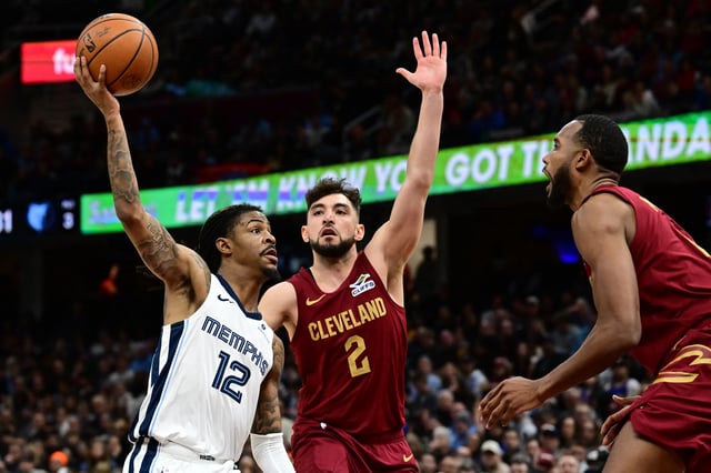 Feb 23, 2025; Cleveland, Ohio, USA; Memphis Grizzlies guard Ja Morant (12) drives to the basket against Cleveland Cavaliers guard Ty Jerome (2) and forward Evan Mobley (4) during the second half at Rocket Arena. Mandatory Credit: Ken Blaze-Imagn Images