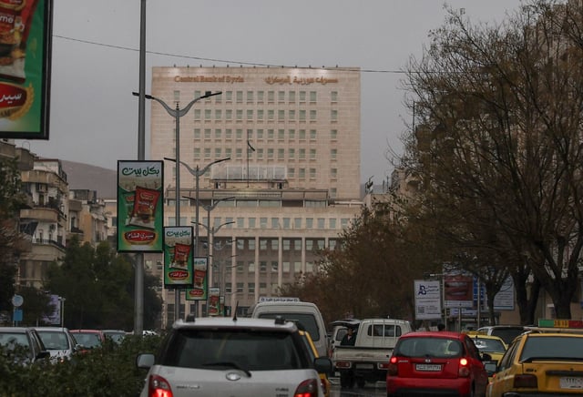 Vehicles drive as the Syrian central bank is seen in the background in Damascus, Syria February 12, 2025. REUTERS/Yamam al Shaar/File Photo
