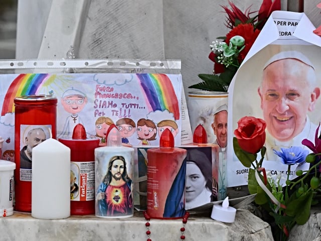 Candles, flowers and a portrait of Pope Francis are laid at the statue of John Paul II outside the Gemelli hospital where Pope Francis is hospitalized, in Rome on February 24, 2025. Pope Francis, in a critical condition in hospital with pneumonia, had a good night and was resting, the Vatican said on February 24, 2025. "The night passed well, the pope slept and is resting", it said in a brief statement as Francis, 88, entered his 14th day at the Gemelli hospital in Rome, making this the longest hospitalization of his papacy. (Photo by Alberto PIZZOLI / AFP)